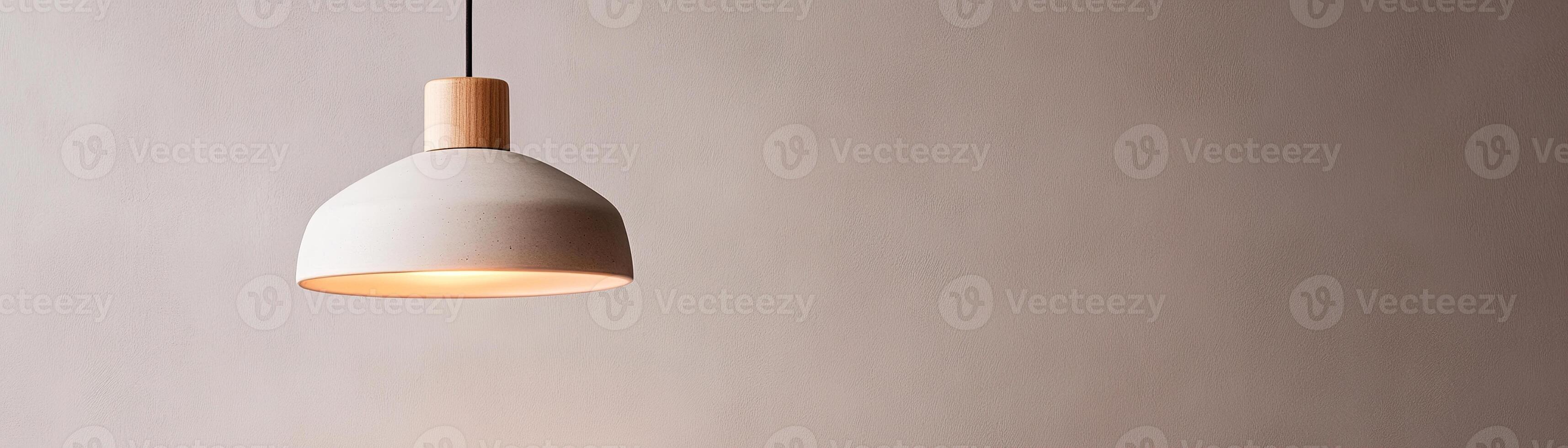 A sleek pendant light with a warm amber glow hangs from the ceiling against a muted gray wall. The minimalistic design enhances the cozy atmosphere while leaving space for text photo