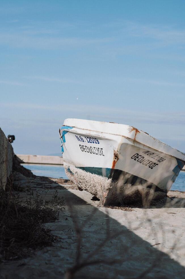 The weathered fishing boat sits docked at the port, with peeling paint and rust, reflecting its years of use photo