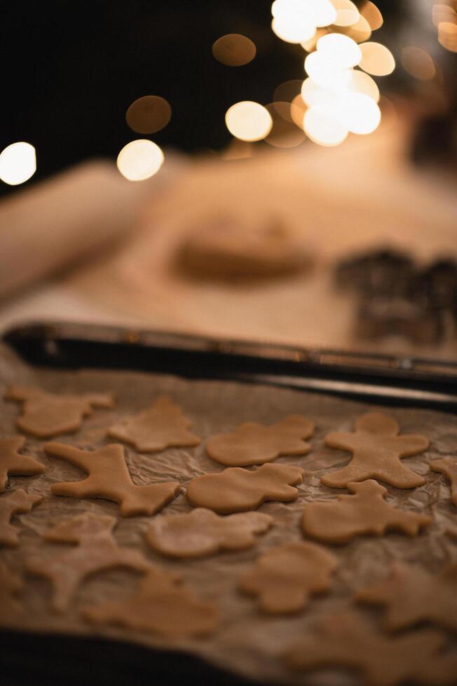 A cozy kitchen scene with gingerbread dough and various shaped cookie cutters on the table. photo