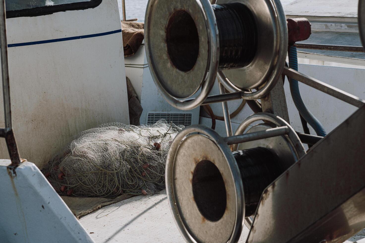 A boat is filled with fishing equipment, including reels and tangled nets photo