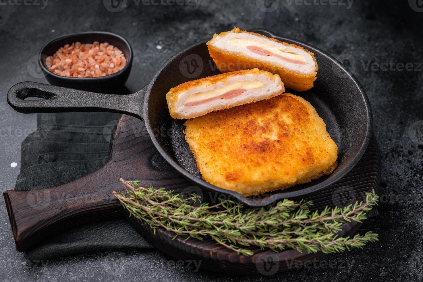 Fried cordon bleu cutlet with cheese and ham in pan. black background. top view photo