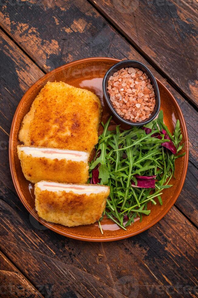 Chicken Fried cordon bleu cutlet on plate with salad. wooden background. top view photo