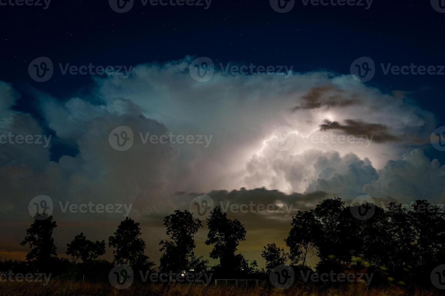 Nighttime sky illuminated by a bolt of lightning over the horizon photo