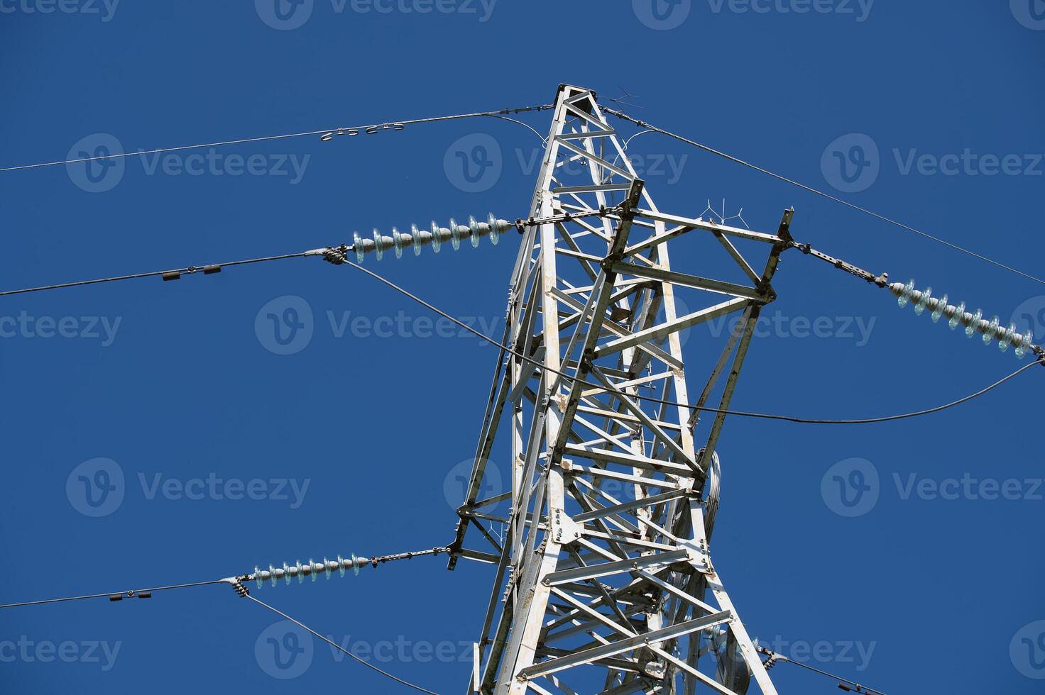Electricity pylon transporting energy through cables under blue sky photo
