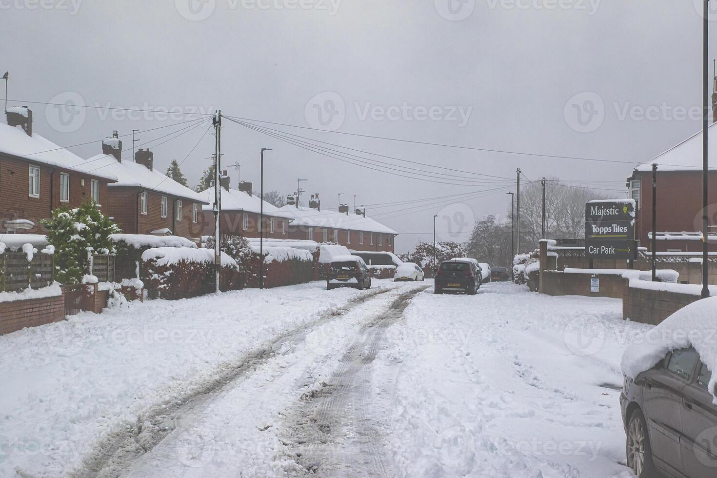 Snow-Covered Residential Street with Parked Cars and Topps Tiles Signage in Harrogate, UK. photo