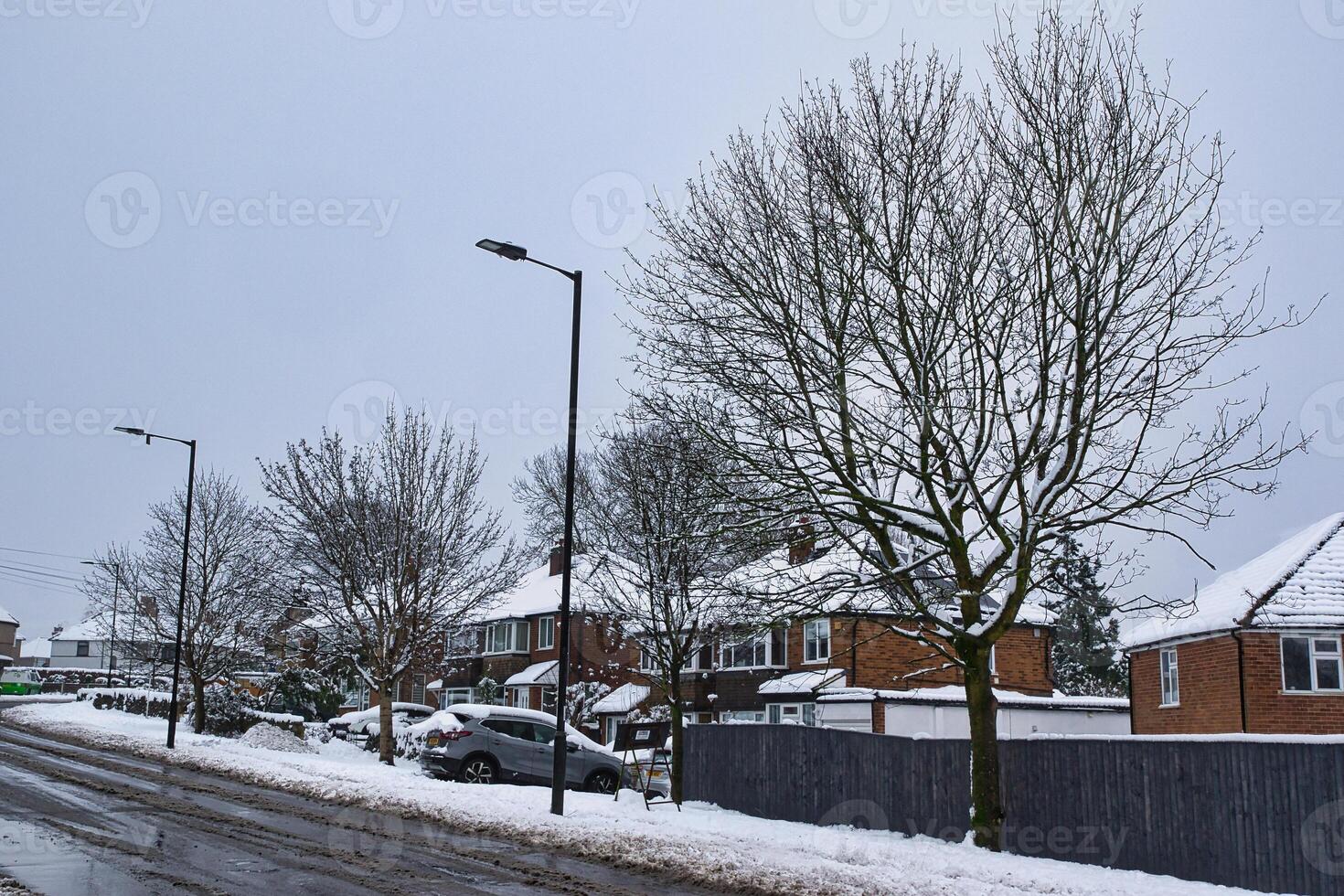 Snow-Covered Suburban Street with Parked Cars and Streetlights in Harrogate, UK. photo