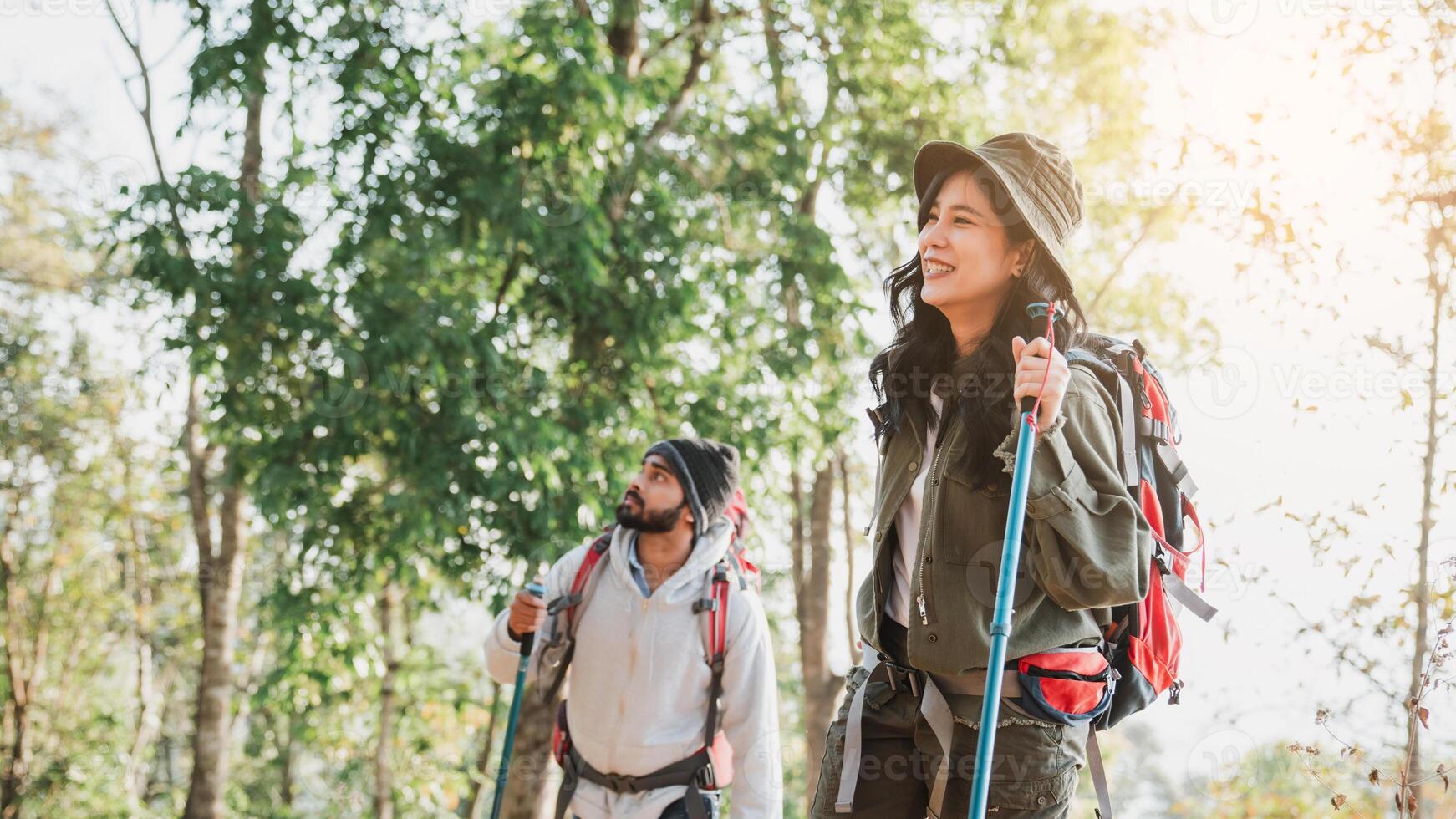 Backpackers traverse a trail through towering trees, experiencing the forest calm ambiance. photo