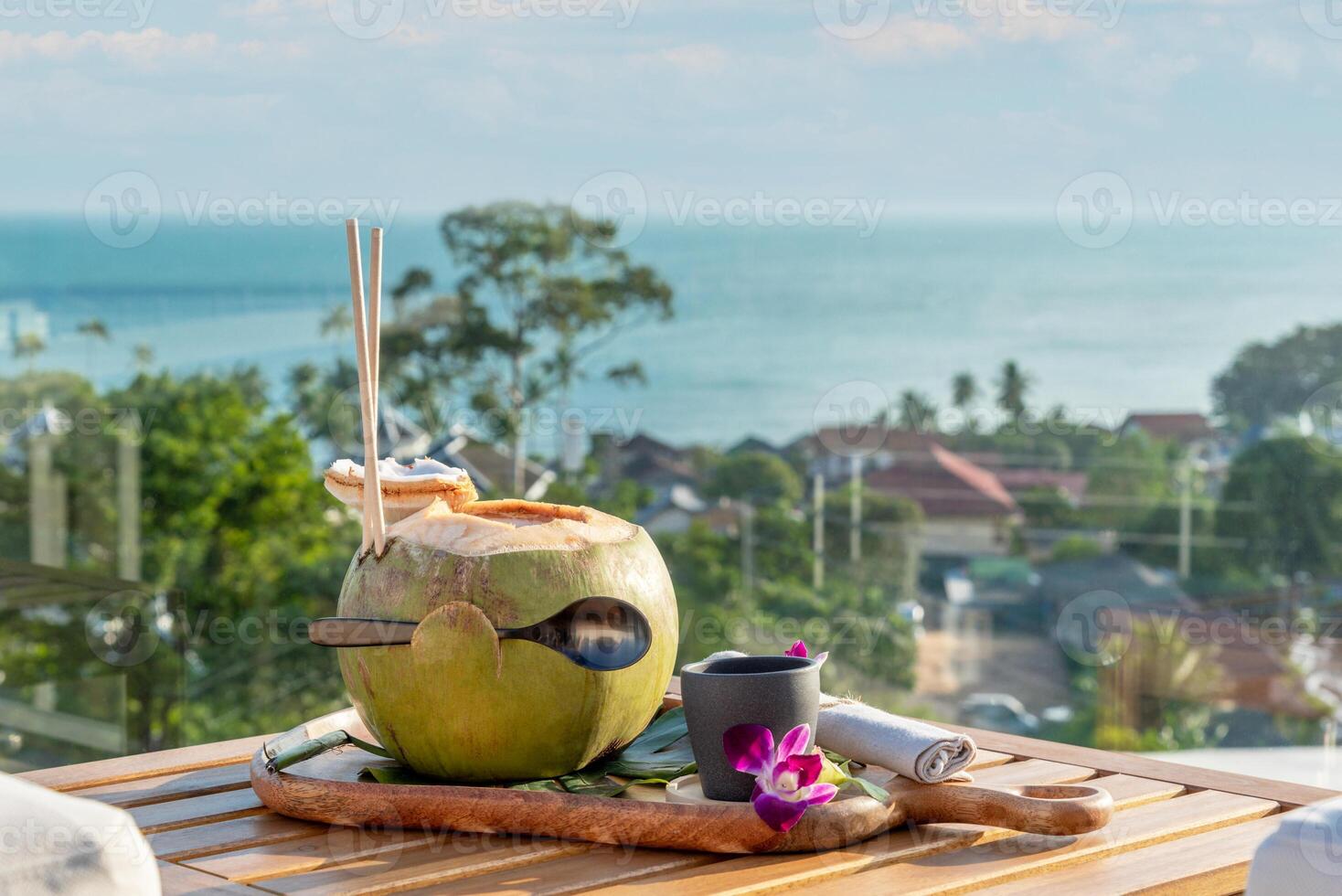 Fresh coconut water with city and sea view in the background at sunset photo