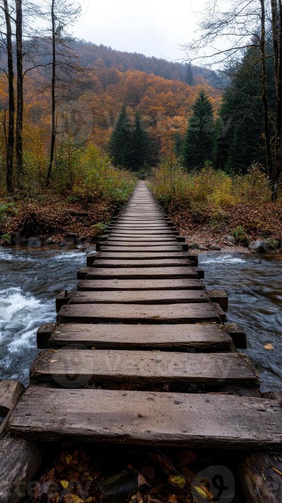 rustic wooden bridge crossing flowing river in autumn photo