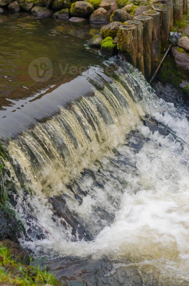 small waterfall cascading over wooden posts, creating a tranquil scene. High quality photo