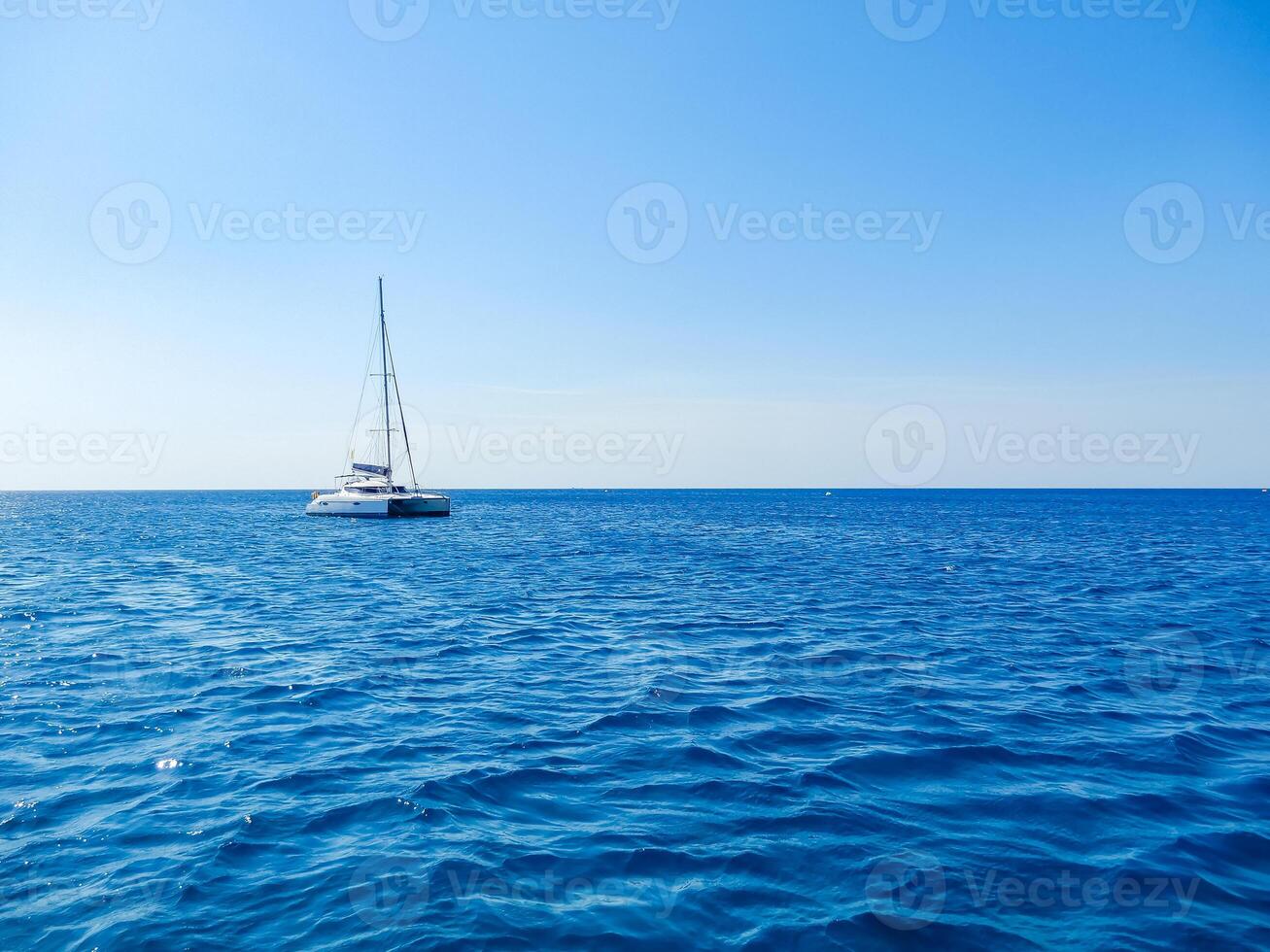 Sailboat drifting on calm blue ocean under clear sky, peaceful and serene scene. High quality photo