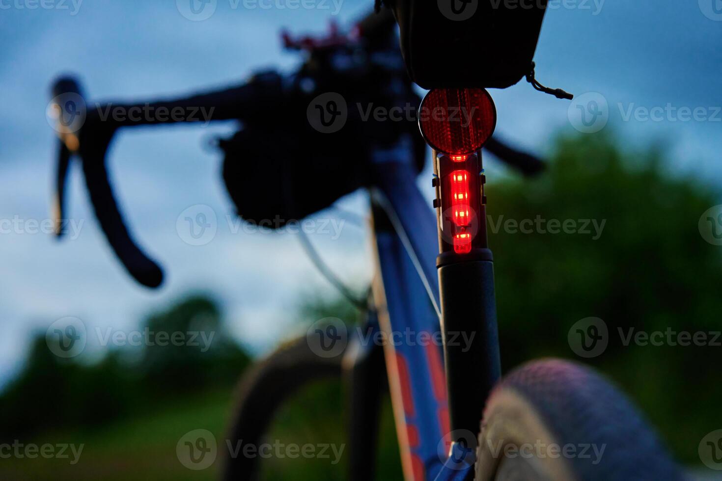 Glowing bicycle tail light in twilight. Red stop light for cyclist visibility and safety during night cycling. Rear led light on bike photo