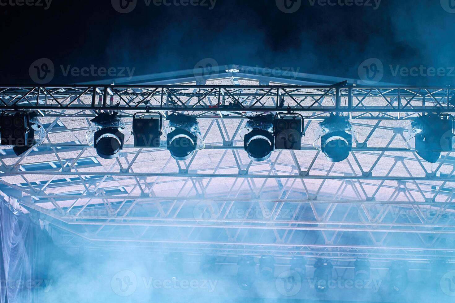 Close-up view of professional stage lighting mounted on metal truss. Bright spotlights at concert stage. Live music event photo