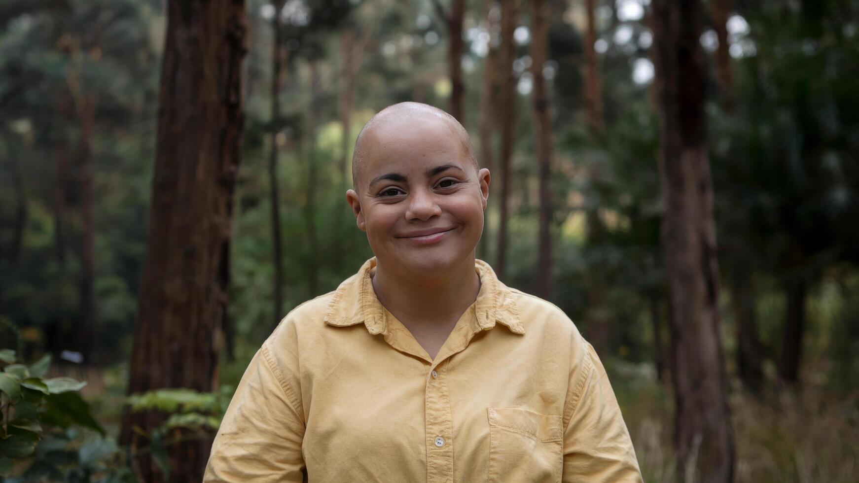 Photo of bald woman with Down syndrome smiling against forest background, capture happiness and connection with nature. Community concept