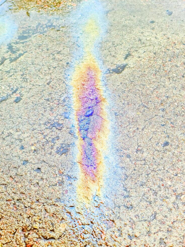 Oil slick in bright colours on the asphalt of an old road. photo