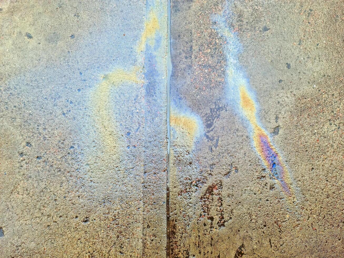 An oil slick in bright colours on the asphalt of an old road. photo