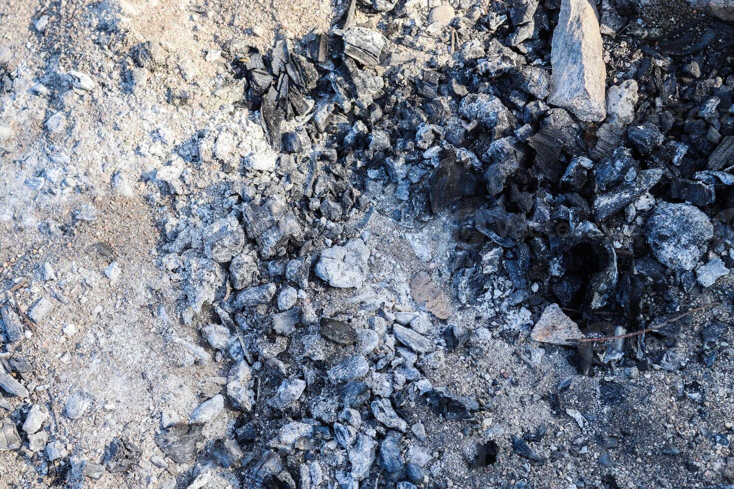 The surface of burnt wood and coal as the remains of a campfire. photo