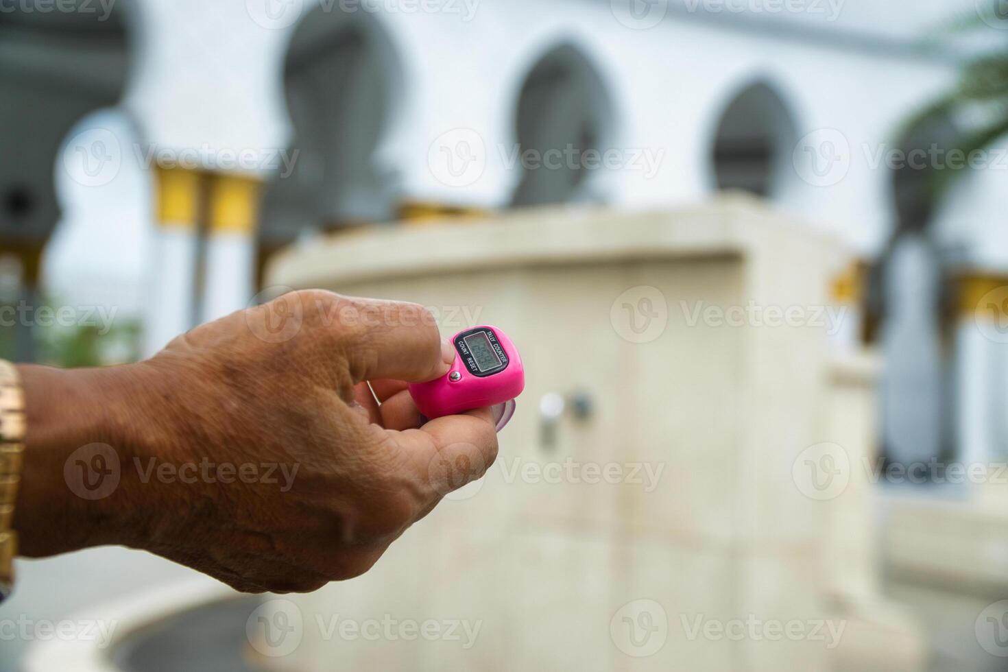 Hands Holding Tally Counter for Counting Dhikr photo