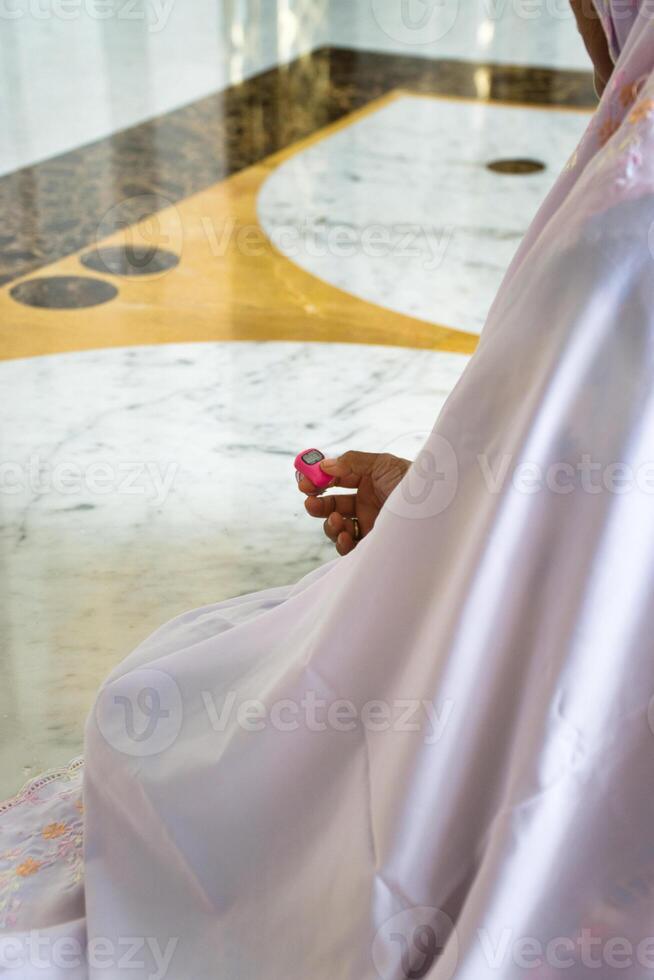 Close-Up of Hands Holding Tally Counter for Counting Dhikr photo