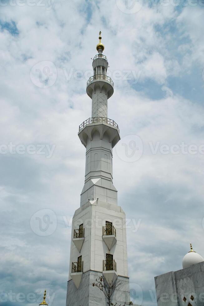Elegant Sheikh Zayed Grand Mosque Minaret Tower Against a Blue Sky with Soft Clouds photo