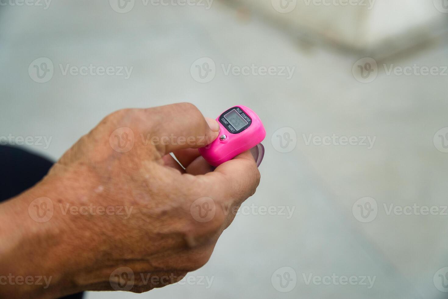 Close Up of Hands Holding Tally Counter for Counting Dhikr photo