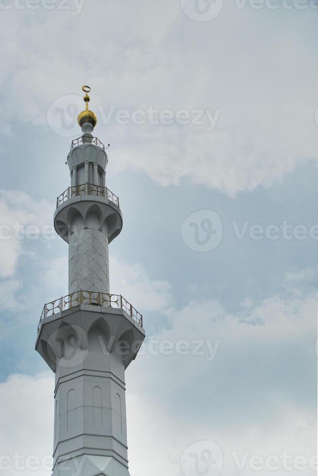 Prominent White Minaret of Sheikh Zayed Grand Mosque Against a Clear Sky photo