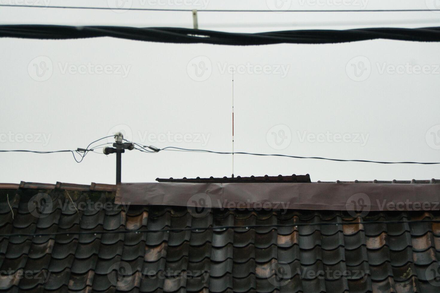 Rooftop With Antenna and Overhead Power Lines on a Cloudy Day photo