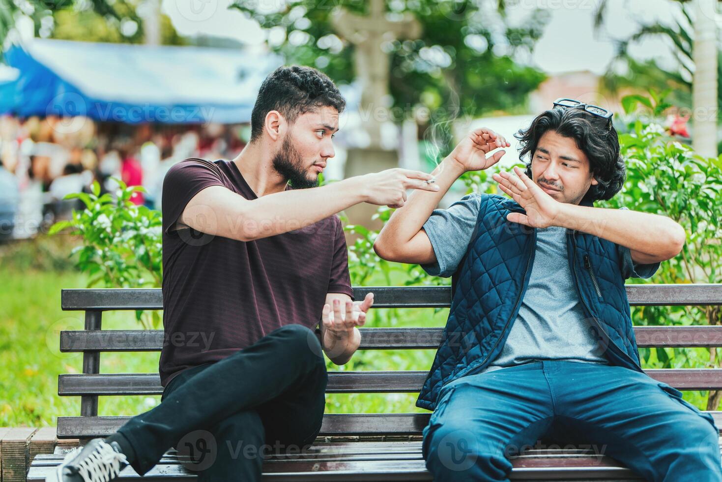 Young man sitting refusing a cigarette in the park. Disgusted guy sitting refusing a cigarette photo