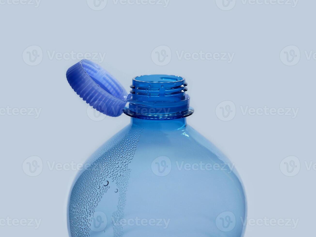 A new mechanism of plastic bottle with a stationary fixed tethered cap. Blue plastic PET water bottle with cup open close up isolated on white. Recycling, environment friendly and ecology concept photo