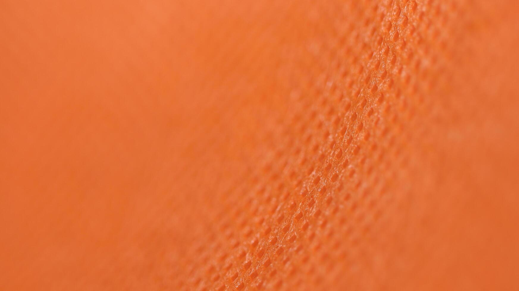 Macro close-up of vibrant orange fabric with rich texture and woven details photo