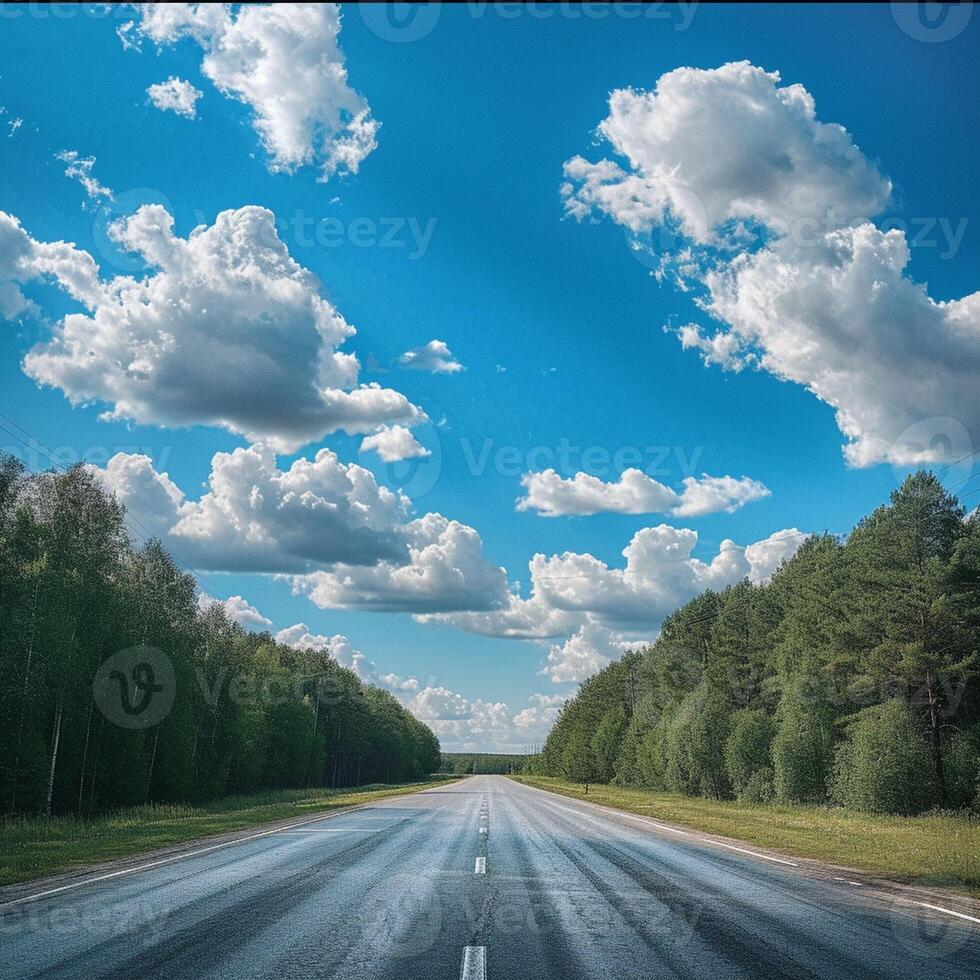 Wide open highway stretching through lush green forests under a bright sky. photo