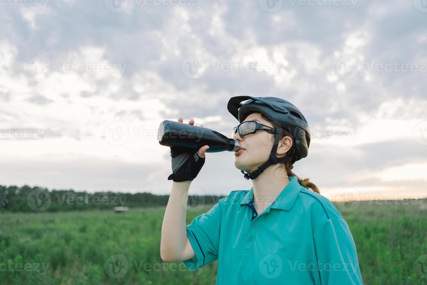 Woman in Helmet Takes a Drink During a Bike Ride photo