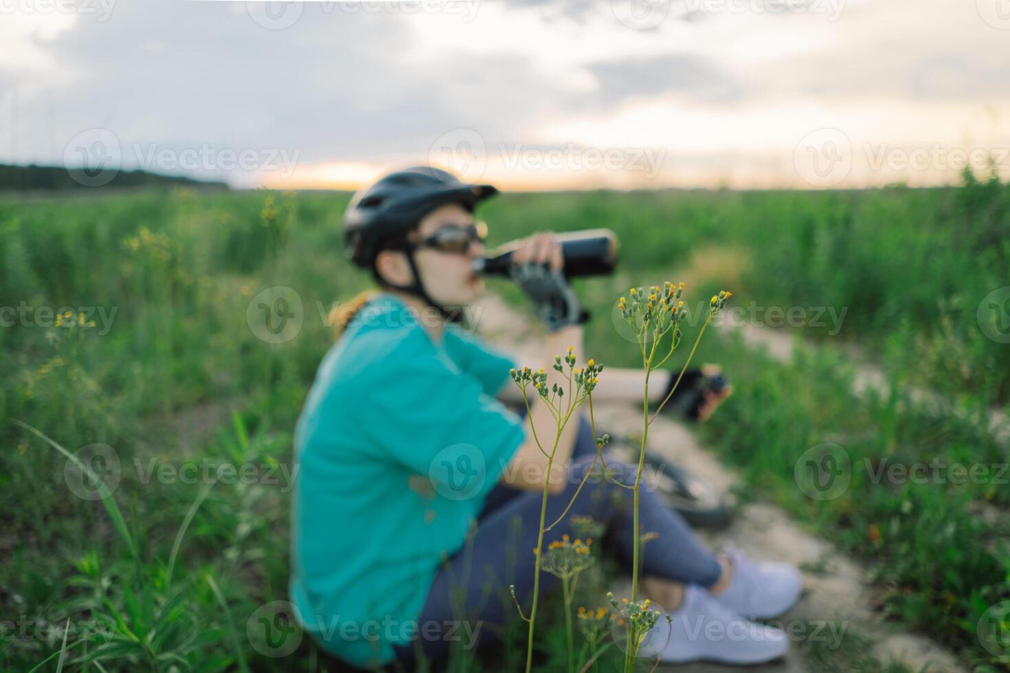 Woman in Helmet Takes a Drink During a Bike Ride photo