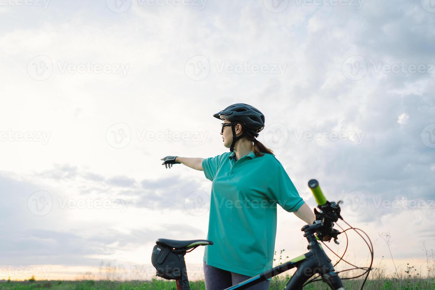 Young Cyclist Looking Up at Cloudy Sky on Sunny Day photo