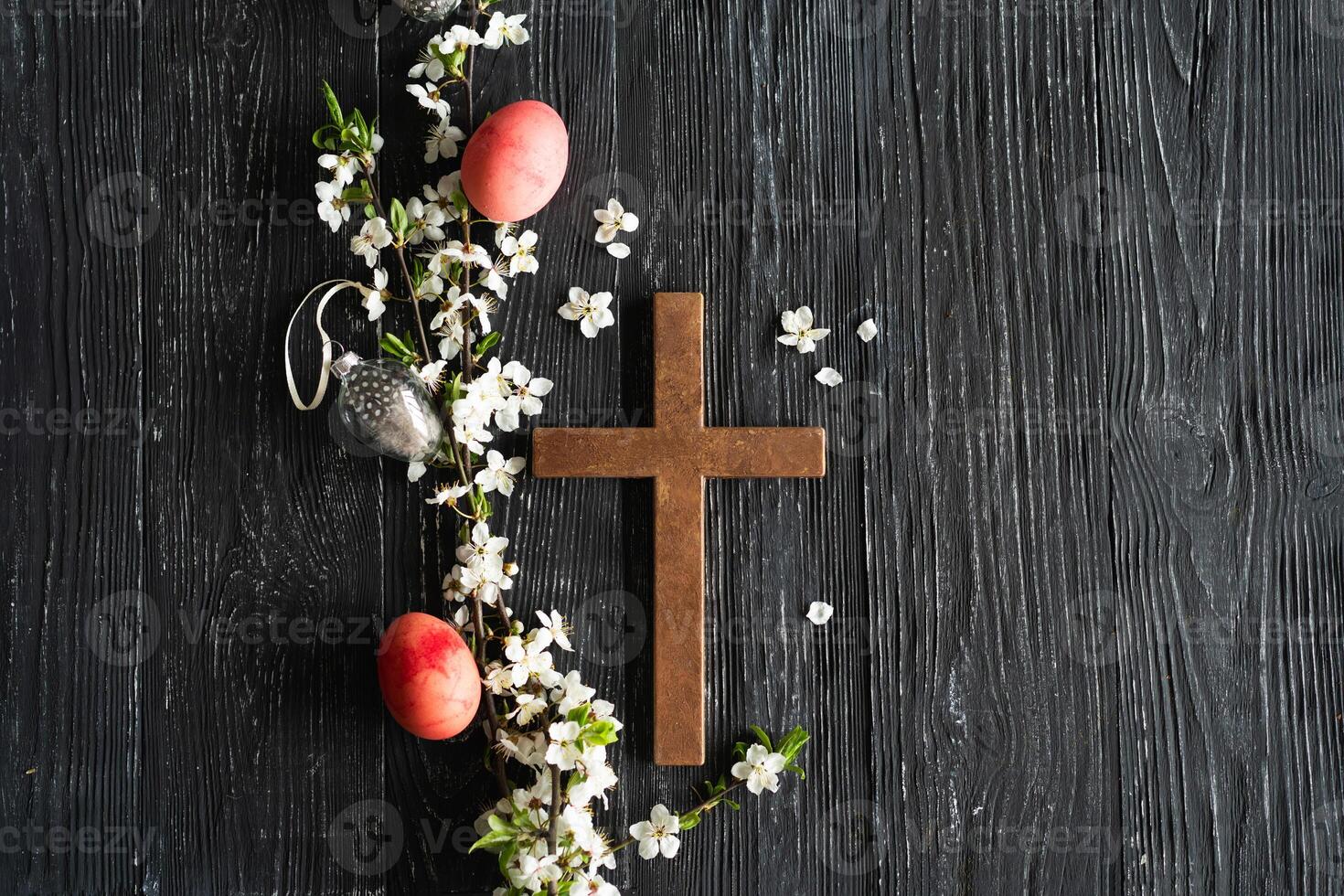 Spring cherry blossoms and Easter eggs and cross on old wooden background photo