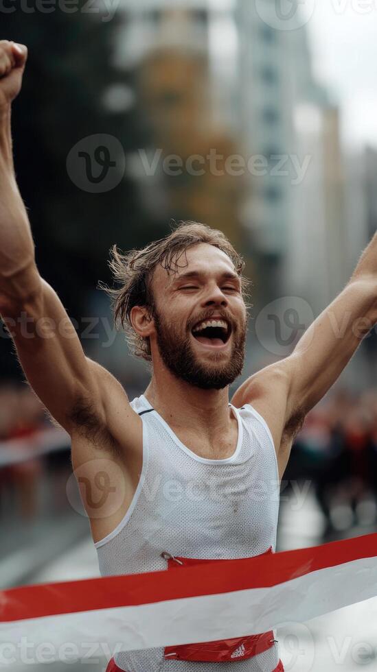 A runner joyfully crosses the finish line with arms raised in celebration. The scene captures the excitement of victory in an urban marathon setting, creating a vibrant atmosphere photo