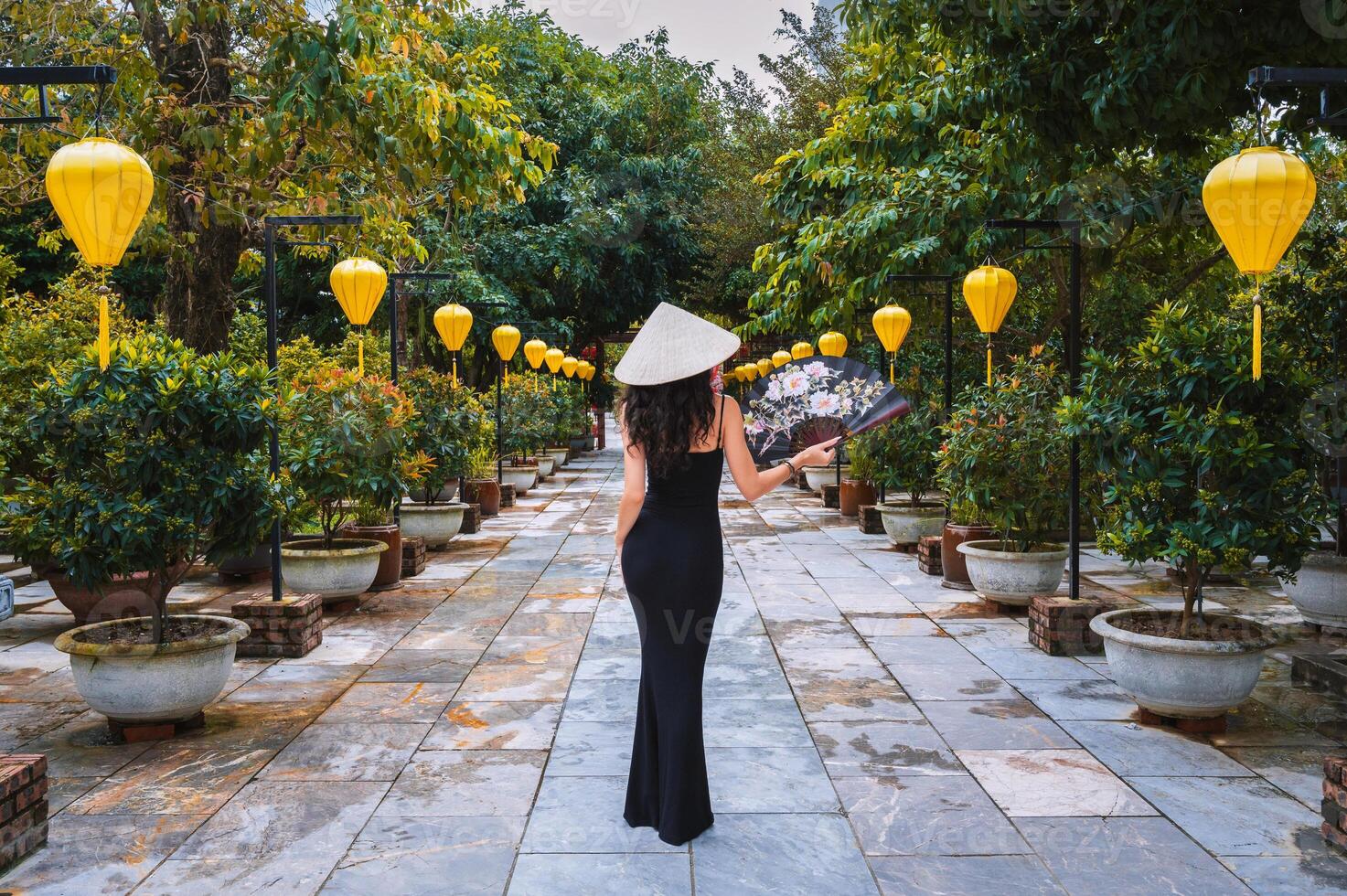 A woman in a traditional Vietnamese hat on the background of an Asian cultural garden decorated with lanterns photo