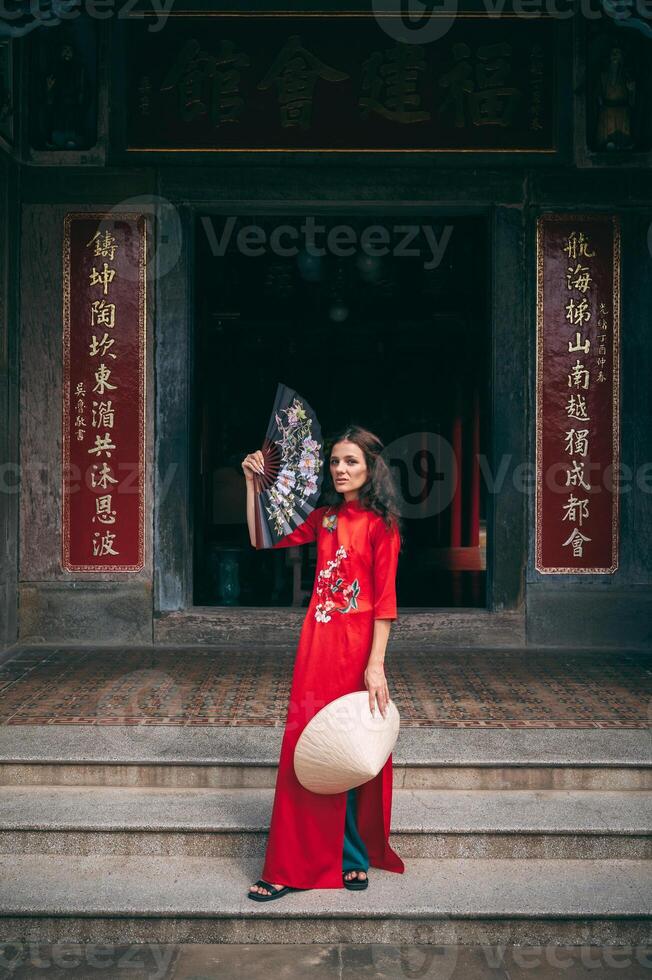 A young woman with Ao Dai dress standing in temple in Hoi An, Vietnam. photo