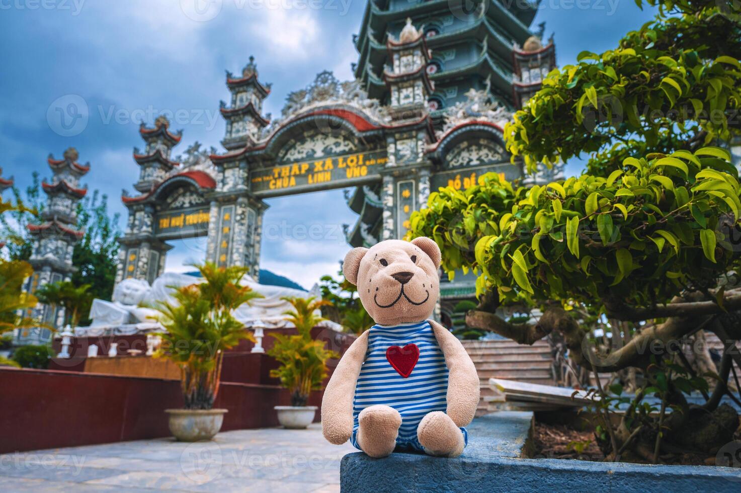 A traveler's bear toy on the background and White Lady Buddha with blue sky at Chua Linh Ung Bai But Temple, Da Nang, Vietnam. photo