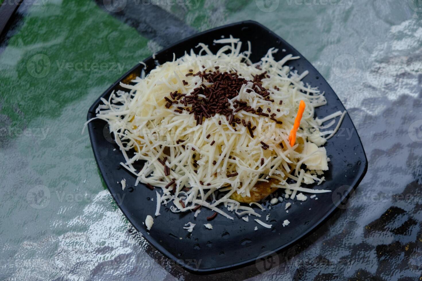 pisang bakar keju. Grilled banana topped with grated cheese and chocolate milk. photo