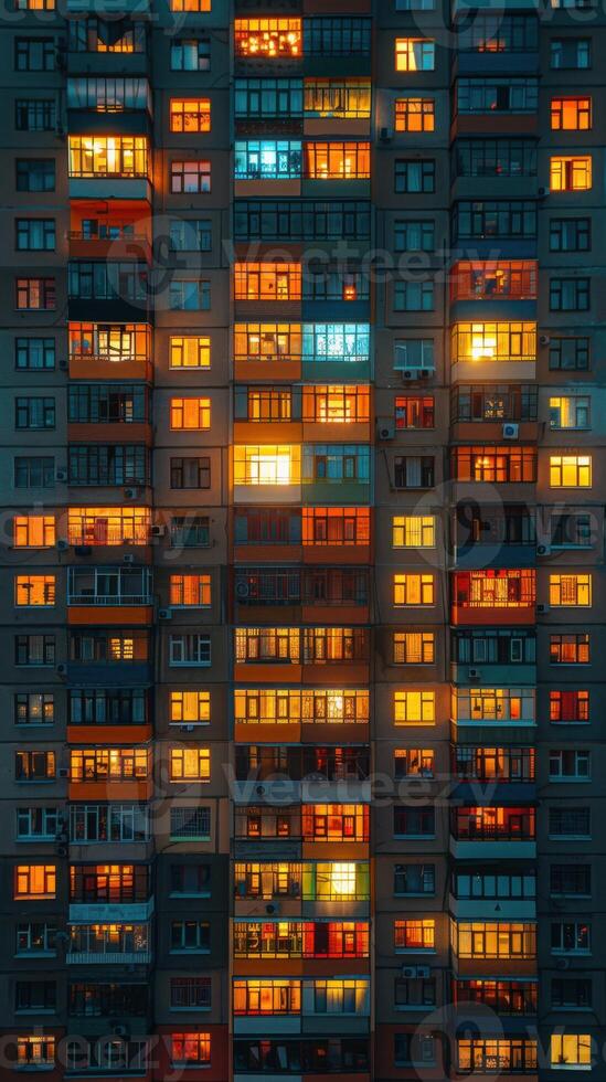 Brightly lit apartment windows glow in various warm hues, creating a stunning urban nightscape. A vibrant reflection of modern city life and architectural beauty photo
