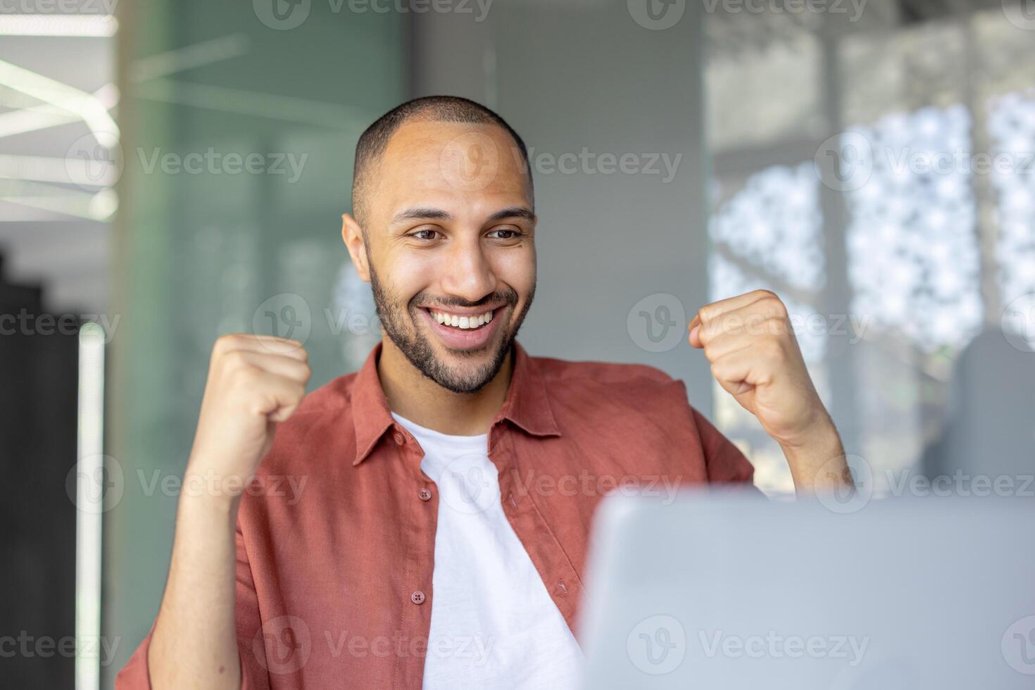 Man close up celebrating successful achievement results, employee received online email notification. Joyfully holding hands up in triumph gesture. photo