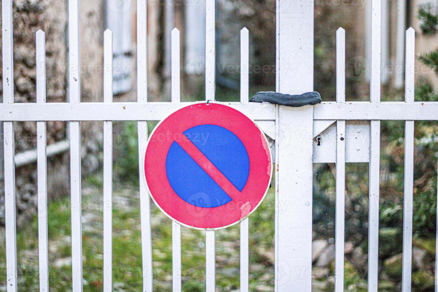 Red and blue no stopping sign on a metallic gate photo