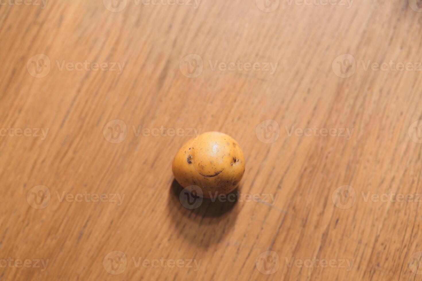 A Cute Potato featuring a Unique Face sitting atop a Wooden Table, full of charm and character photo