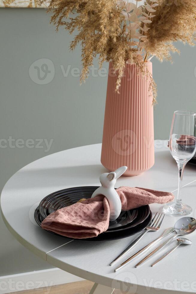 An Elegant Table Setting Featuring a Decorative Bunny and a Modern Vase for Style photo