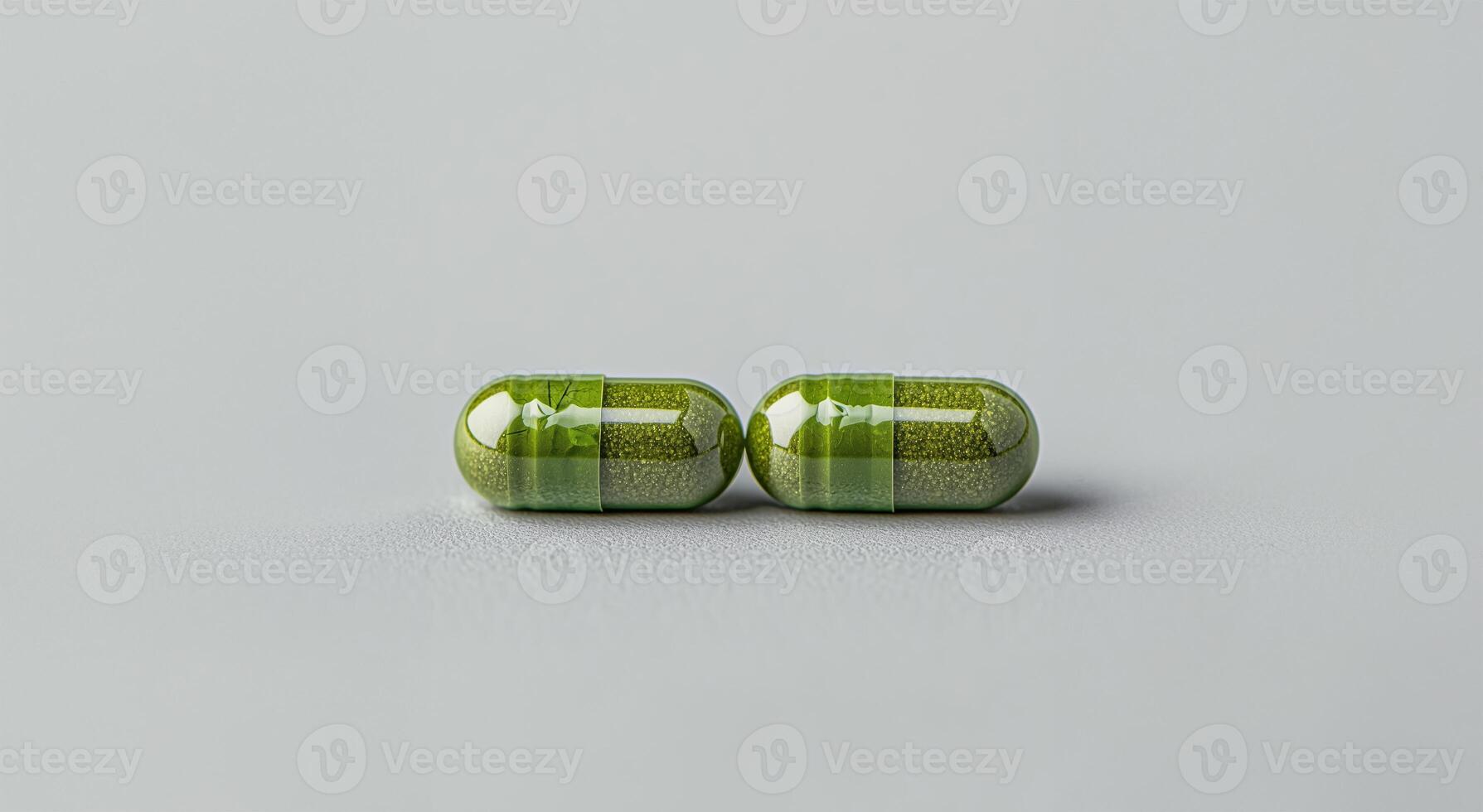 Two green capsules placed on a textured gray surface. photo