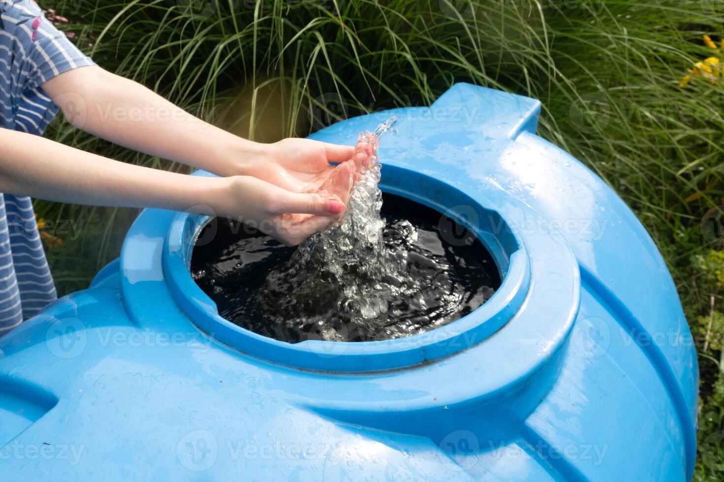 Faceless girl washes her hands in a barrel of rainwater. Rain water harvesting architecture photo