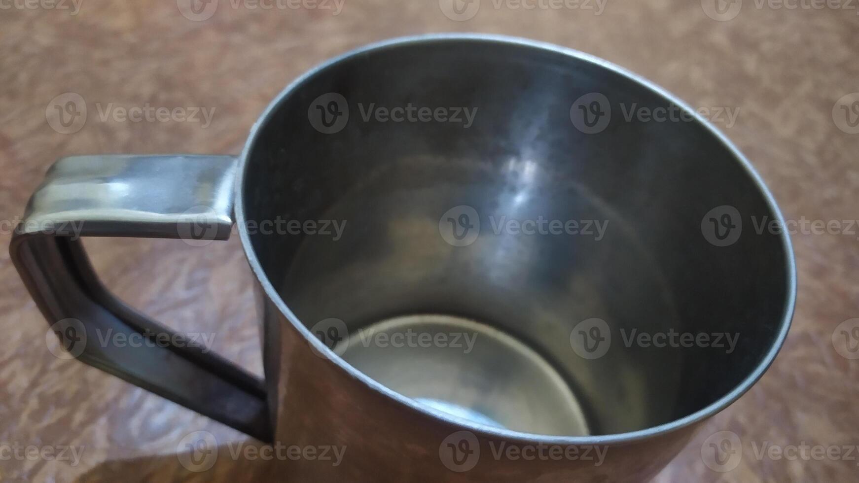 a metal cup with a handle on a table, top photo