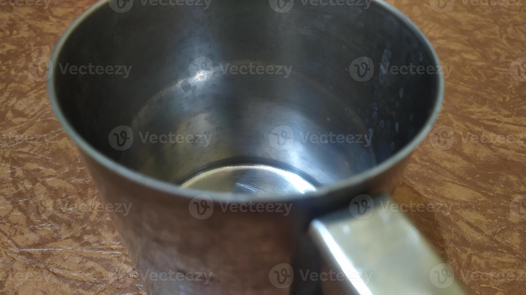 a metal cup with a handle on a table photo