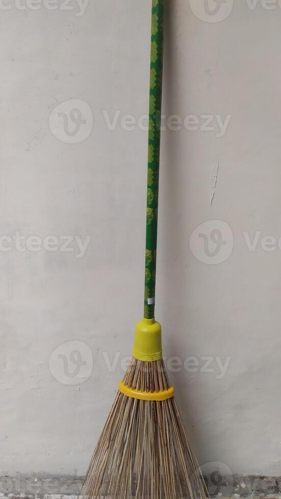 a broom with a yellow handle and green handle. photo